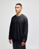 A black Champion Reverse Weave® adult crew sweatshirt displayed on a model, featuring a logo on the sleeve.