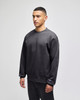A grey crewneck sweatshirt on a model, featuring a logo on the sleeve and a relaxed fit.