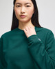 A green crewneck sweatshirt featuring long sleeves and a logo on the sleeve.