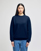 A navy blue crewneck sweatshirt is worn by a model, featuring a small logo on the sleeve.