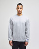 A grey Champion Powerblend® adult crewneck sweatshirt with a logo, featured on a model in casual attire.