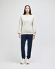 A woman stands in a light grey Champion Powerblend® adult crewneck sweatshirt and navy jogger pants, wearing white sneakers.