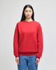 A red crewneck sweatshirt displayed on a model, featuring long sleeves and a logo.