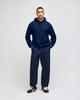 A navy blue pullover hooded sweatshirt on a model, paired with matching navy pants. The sweatshirt features a logo.