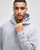A grey hooded sweatshirt with a front pocket and a logo on the sleeve, modelled by a person.