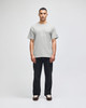 A short-sleeve t-shirt in grey with a logo, modelled by a man, paired with black trousers.