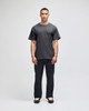 A model wearing a grey Champion adult short-sleeve T-shirt paired with black pants. The shirt features a logo.