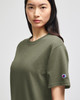 An olive green Champion adult short-sleeve t-shirt displayed on a model, featuring a small logo on the sleeve.