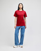 A model wearing a red Champion adult short-sleeve t-shirt paired with blue jeans and white sneakers.
