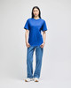 A model wearing a blue Champion adult short-sleeve t-shirt paired with light blue jeans. The shirt has a logo.