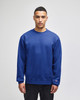 A model wearing a blue Champion adult sweatshirt with a logo on the sleeve, set against a neutral background.