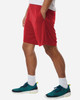 Men's performance shorts in red, featuring side pockets, paired with athletic shoes in teal and black.