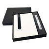 A white notebook with a black band and a pen, presented in a sleek black gift box.