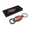 A drink bottle opener in round shape with a wooden finish and a black metal keyring, presented in a sleek box.