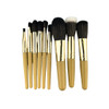 A set of nine makeup brushes with gold handles and varying brush types, presented in a neat arrangement.