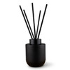 A black botanical reed diffuser with five black reeds, designed for fragrance dispersal.