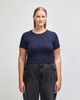 A navy blue crop fitted t-shirt on a model, paired with black high-waisted jeans. The shirt has a logo.