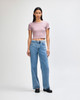 A fitted women's crop T-shirt in soft pink, paired with high-waisted blue jeans. The model stands against a light background.