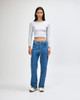 A fitted grey long sleeve crop top paired with loose blue jeans, modelled by a standing woman.