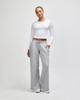 A fitted white long-sleeve crop top paired with grey wide-leg trousers, featuring pockets and a relaxed fit.