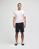 A man wearing a pink t-shirt and black cotton gym shorts, featuring a logo on the shorts.