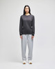 A model wearing a grey Champion long-sleeve T-shirt paired with grey sweatpants and sneakers. The shirt has a logo.