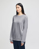 A grey Champion adult long-sleeve t-shirt displayed on a model, featuring a logo on the sleeve.