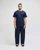 A navy blue short sleeve t-shirt displayed on a model, paired with matching navy pants, featuring a logo on the shirt.