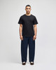 A black short sleeve T-shirt worn with navy blue pants, featuring a logo on the T-shirt.