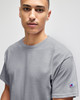 A grey Champion Adult Jersey Short Sleeve T-Shirt displayed on a model, featuring a logo on the sleeve.