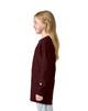 A maroon long sleeve youth t-shirt displayed on a model, featuring a logo on the sleeve.