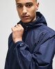 A navy full-zip anorak jacket with a hood, featuring an emblem on the sleeve.