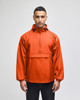 An orange packable anorak jacket with a hood and a front pocket, featuring a logo on the chest.