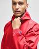 A red packable anorak jacket with a hood and adjustable features, featuring a logo on the sleeve.