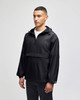 A black packable anorak jacket with a hood, featuring an adjustable drawstring and front pocket, worn by a male model.