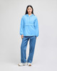 A packable anorak jacket in light blue, featuring a hood and a front pocket, worn with denim jeans.