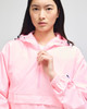 A pink packable anorak jacket featuring a half zip and an adjustable hood, with a logo on the sleeve.