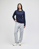 A model stands wearing grey fleece track pants with pockets and a navy long-sleeve top. The outfit includes a logo.