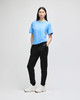 A female model wearing a blue t-shirt and black fleece joggers, featuring a logo on the joggers.