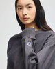 A grey cropped hoodie featuring long sleeves and a small logo on the sleeve.