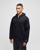 A black full-zip hooded sweatshirt featuring a logo, shown on a model standing straight.
