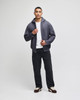 A model wearing a grey Champion Powerblend® full-zip hooded sweatshirt with a white shirt and black pants.