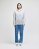 A grey full-zip hooded sweatshirt displayed on a model, paired with blue jeans. The sweatshirt features a logo.