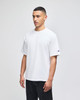 A white Champion Adult Heritage Jersey T-Shirt on a model, featuring a logo on one sleeve.