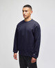 A navy blue Champion Adult Heritage Jersey T-Shirt displayed on a model, featuring a small logo on the sleeve.