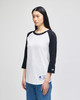 A black and white Champion Adult Raglan Baseball T-Shirt with long sleeves, featuring a logo on the hem.