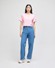 A cropped short sleeve t-shirt in pink, paired with high-waisted blue jeans, showcased on a model.