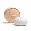 A squishy toy shaped like a steamed bun, featuring a round, woven base and a white bun-like top.
