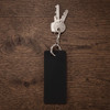 A black rectangular keychain attached to several metal keys on a wooden surface.