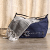 A navy cooler bag with a grey towel, featuring a logo on both items. The towel has a patterned design.